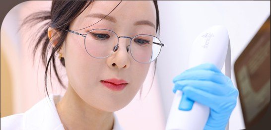 안경을 쓴 의사가 시술 기기를 들고 집중하는 모습